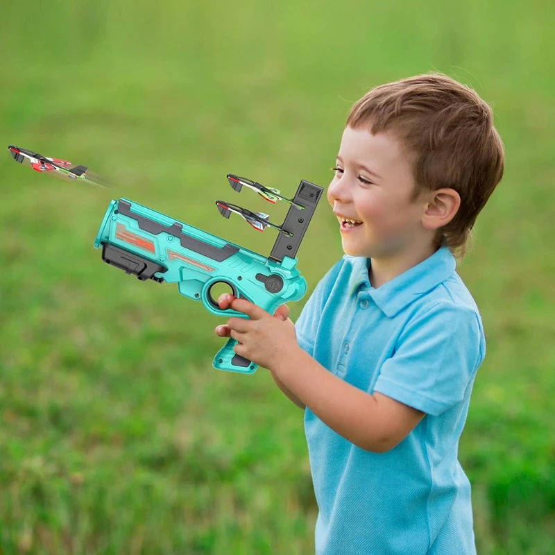 Child holding a blue airplane launcher on a grassy lawn