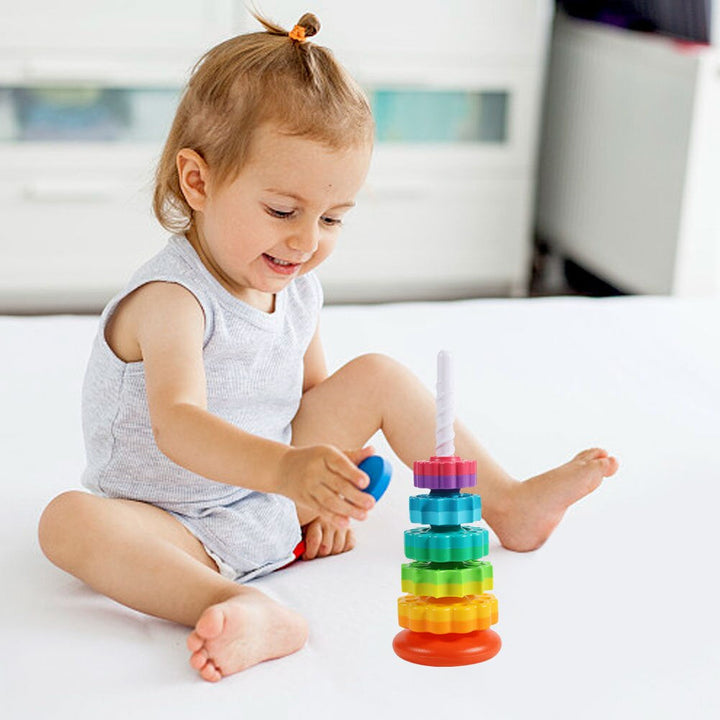 Child holding a blue disc beside a colorful stacking tower