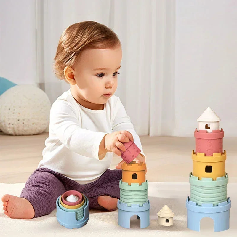 Child stacking pastel castle cups beside another tower and nested pieces