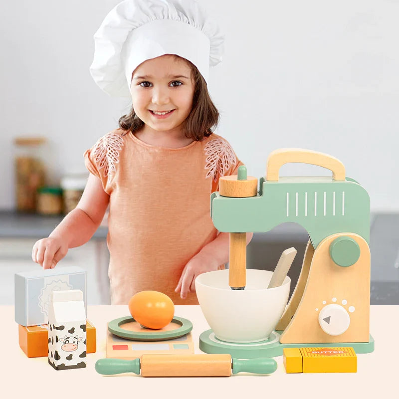 Child in a chef hat beside a green wooden mixer play set and pretend baking ingredients