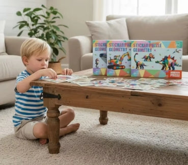 Child working on sticker puzzle sheets at a table with themed puzzle boxes