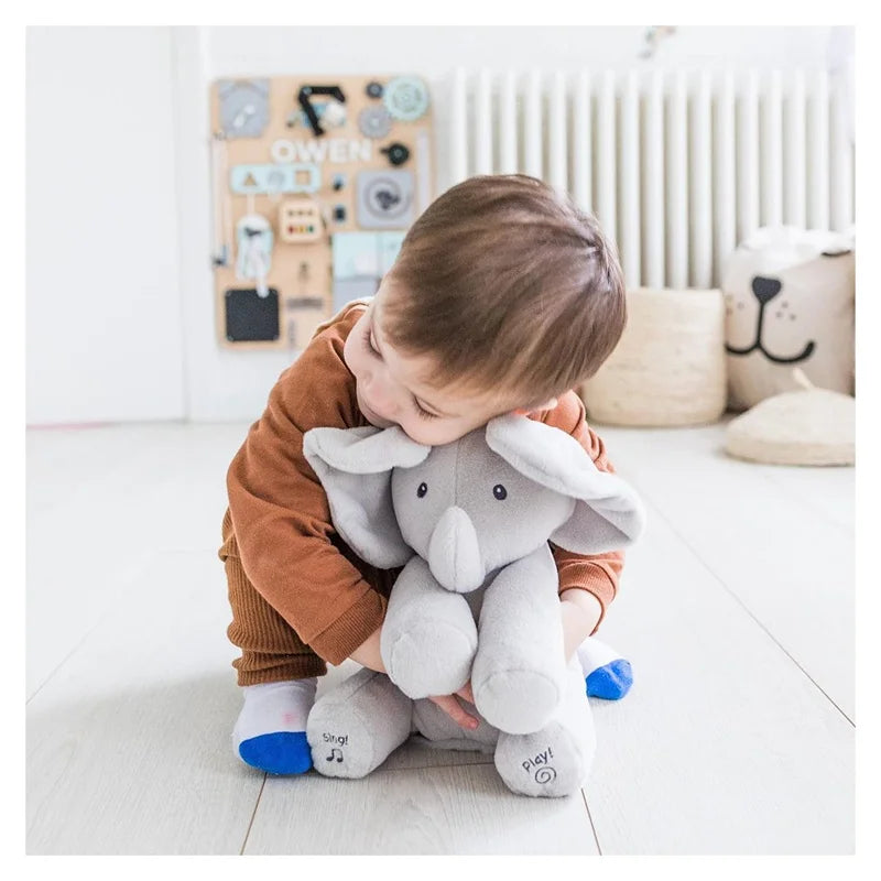 Young child cuddling a gray elephant plush with its ears folded forward