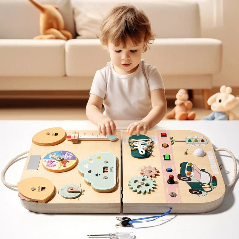 Child playing with a wooden busy board case opened flat to show weather dials, switches, and gears.