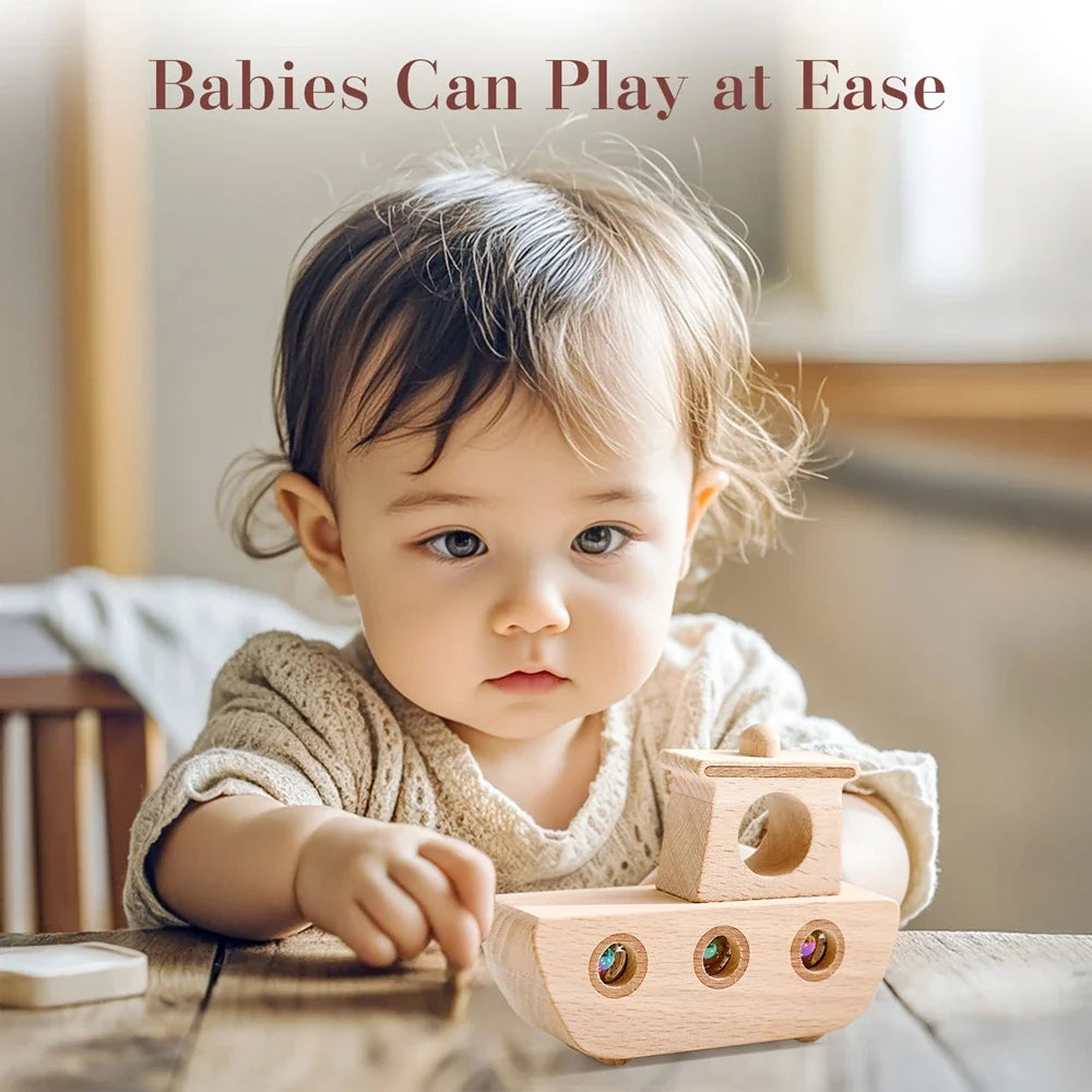 Child reaching toward a wooden boat toy with colorful marbles on a table.