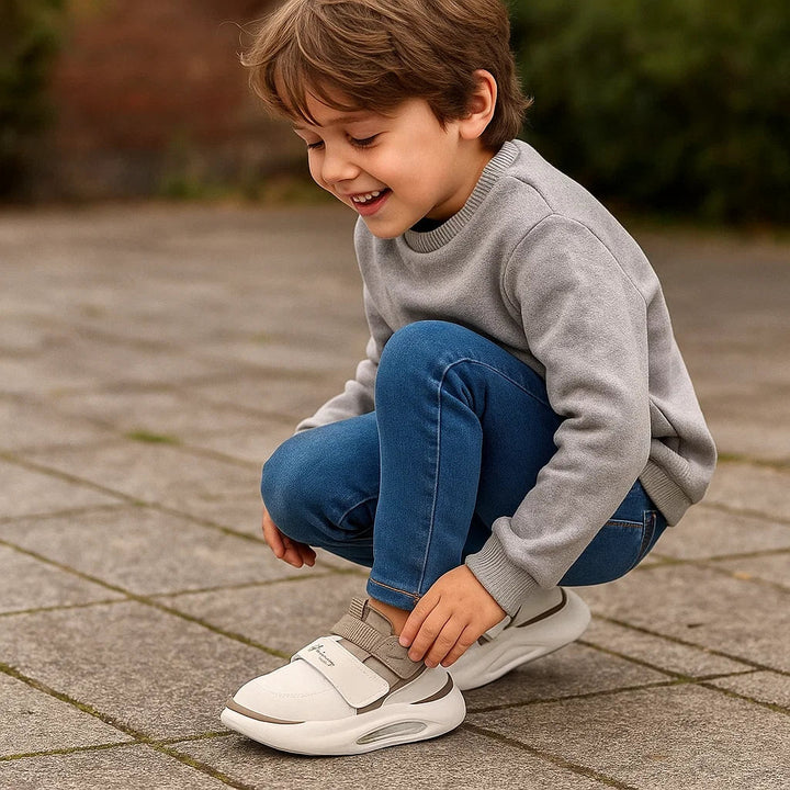Child fastening a white sneaker while crouching on a paved path