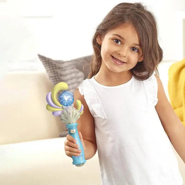 Child in a white dress holding a blue toy wand with a crescent-shaped top