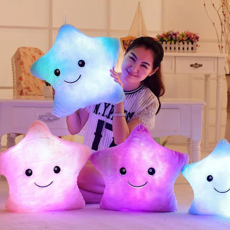 Child holding a glowing blue star pillow beside illuminated pink and purple star pillows