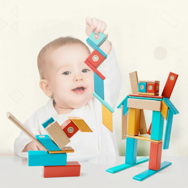 Child holding connected wooden magnetic blocks beside robot and bird-shaped builds