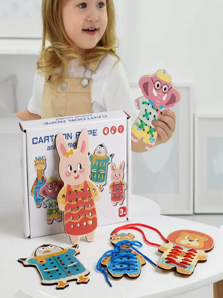 Child holding an elephant lacing board beside a box and other animal boards