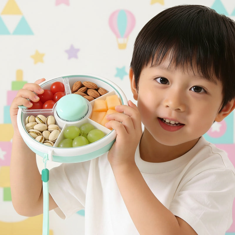 Child holding a green five-compartment snack box filled with assorted snacks
