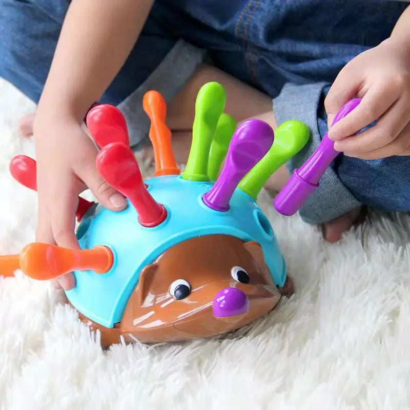 Child holding a purple quill above the blue back of a hedgehog learning toy