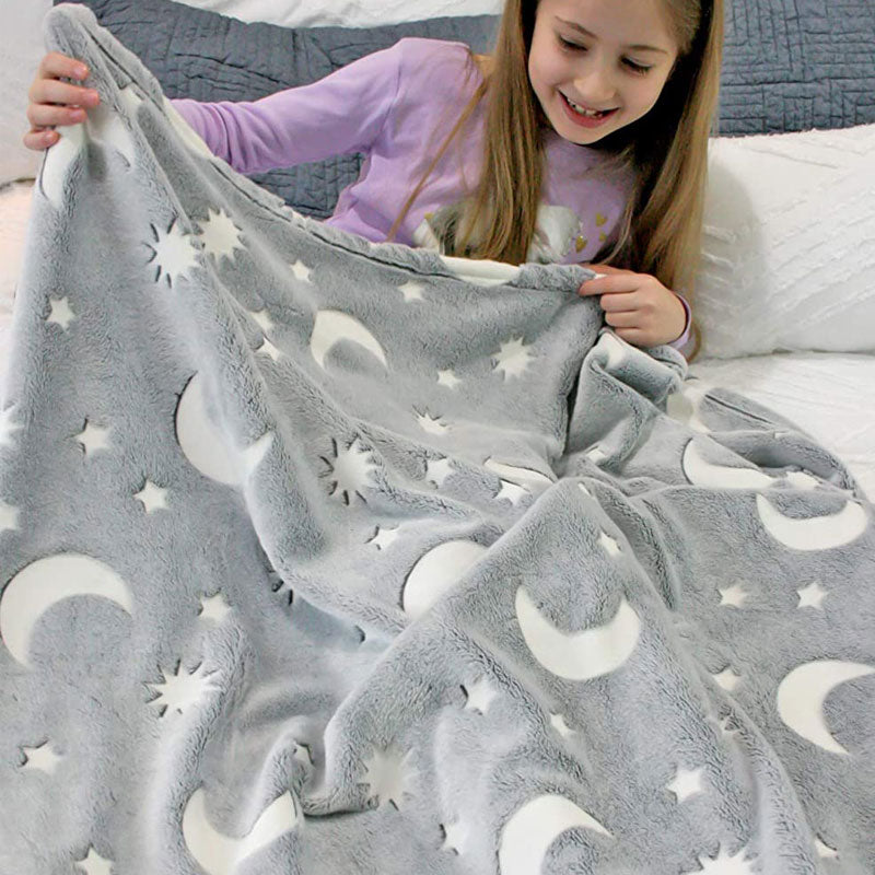 Child holding a plush gray blanket with white sun, moon, and star patterns