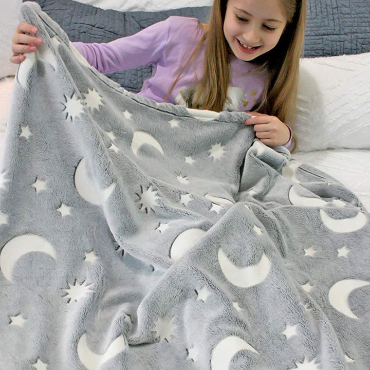 Child holding a plush gray blanket with white sun, moon, and star patterns