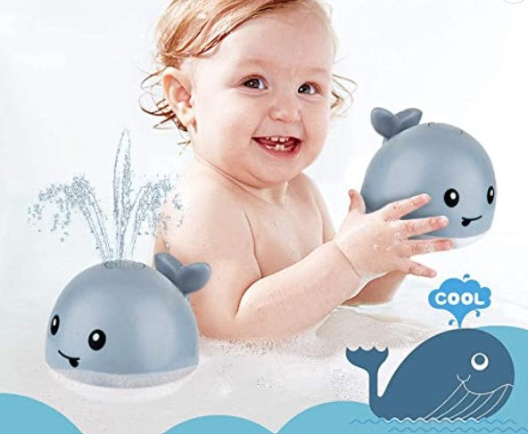 Child holding a gray whale bath toy, with a water-spray demonstration beside them.