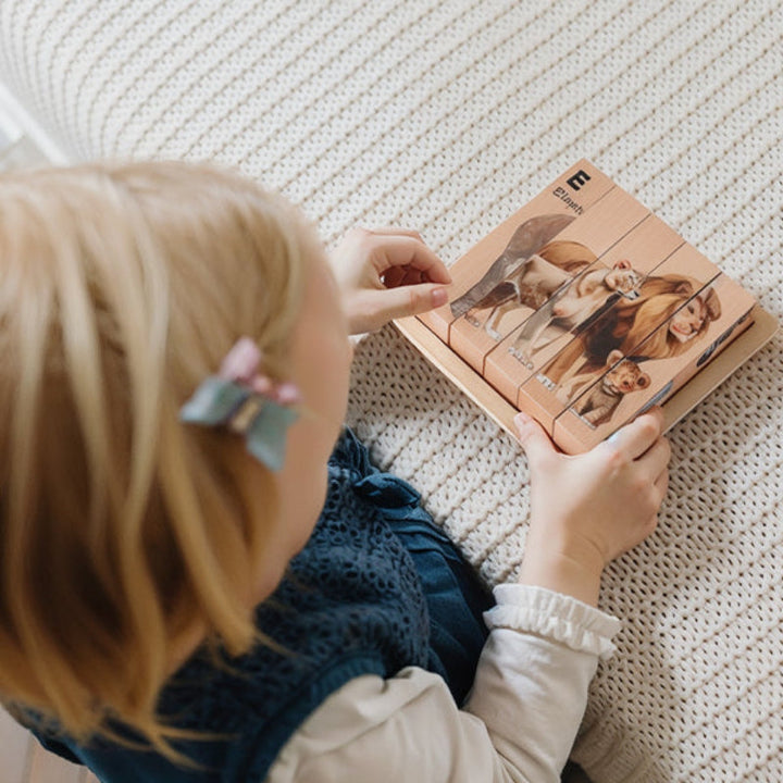 Child holding a wooden animal block puzzle while arranging the pieces