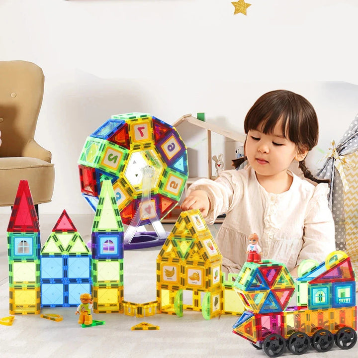 Child building with colorful magnetic tiles arranged as houses and wheeled vehicles