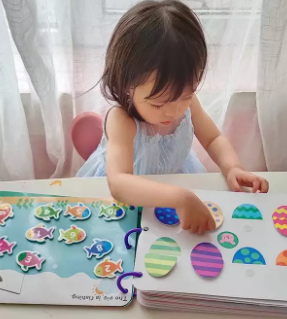 Child exploring number and patterned egg activities in an open matching book