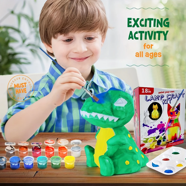 Child painting a green dinosaur lamp at a table with colorful paints, brushes, and palettes.