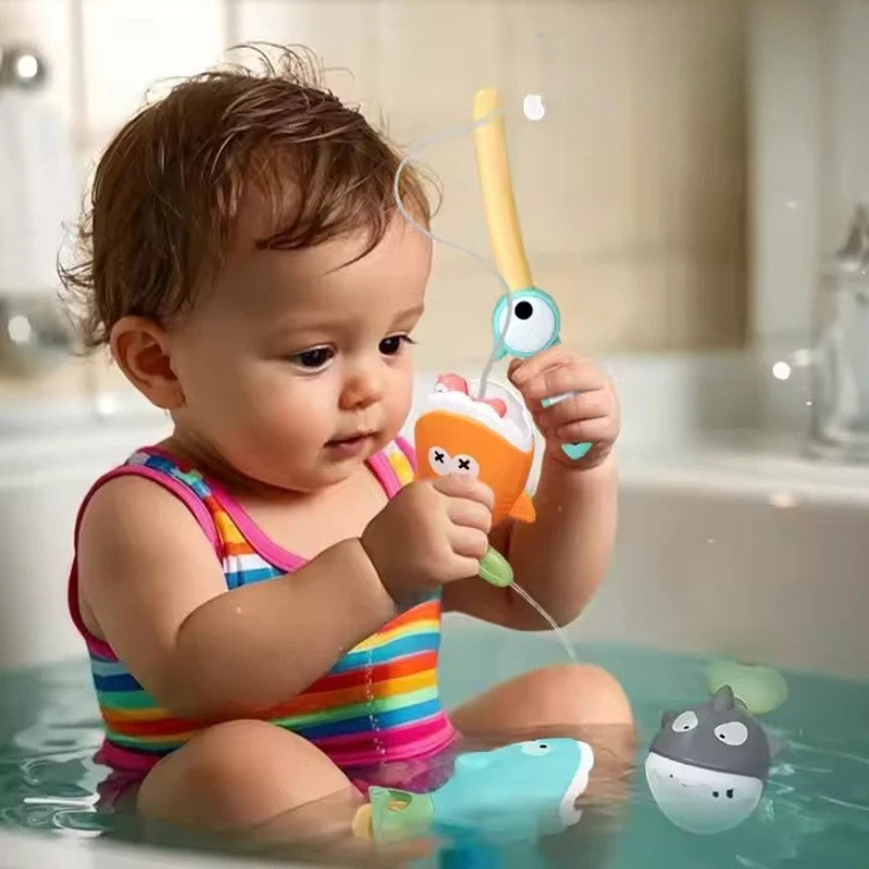 Child holding the fishing rod and an orange fish while playing in the bath