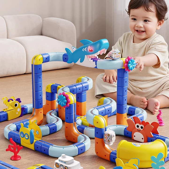 Child playing with a multilevel ocean-themed train track beside a sofa