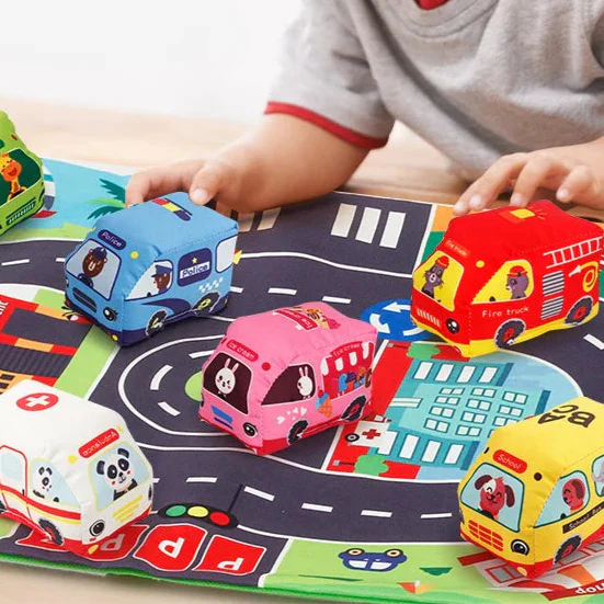 Child moving a blue soft toy vehicle along the printed roads of the city play mat