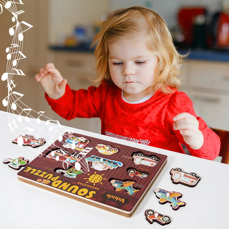 Child in a red sweater playing with a wooden vehicle sound puzzle