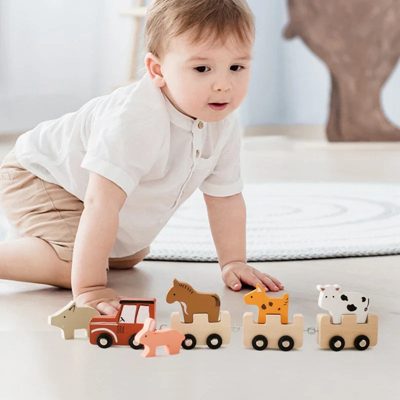 A young child beside a wooden animal train with animal figures riding on three cars.