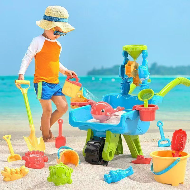 Child playing at the beach with a blue wheelbarrow, sand mill, shovel, and buckets