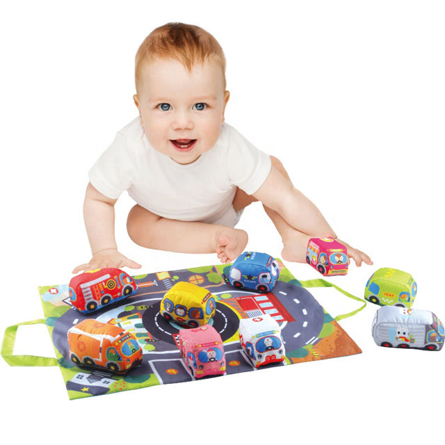 Child playing with colorful soft toy cars on a printed road mat