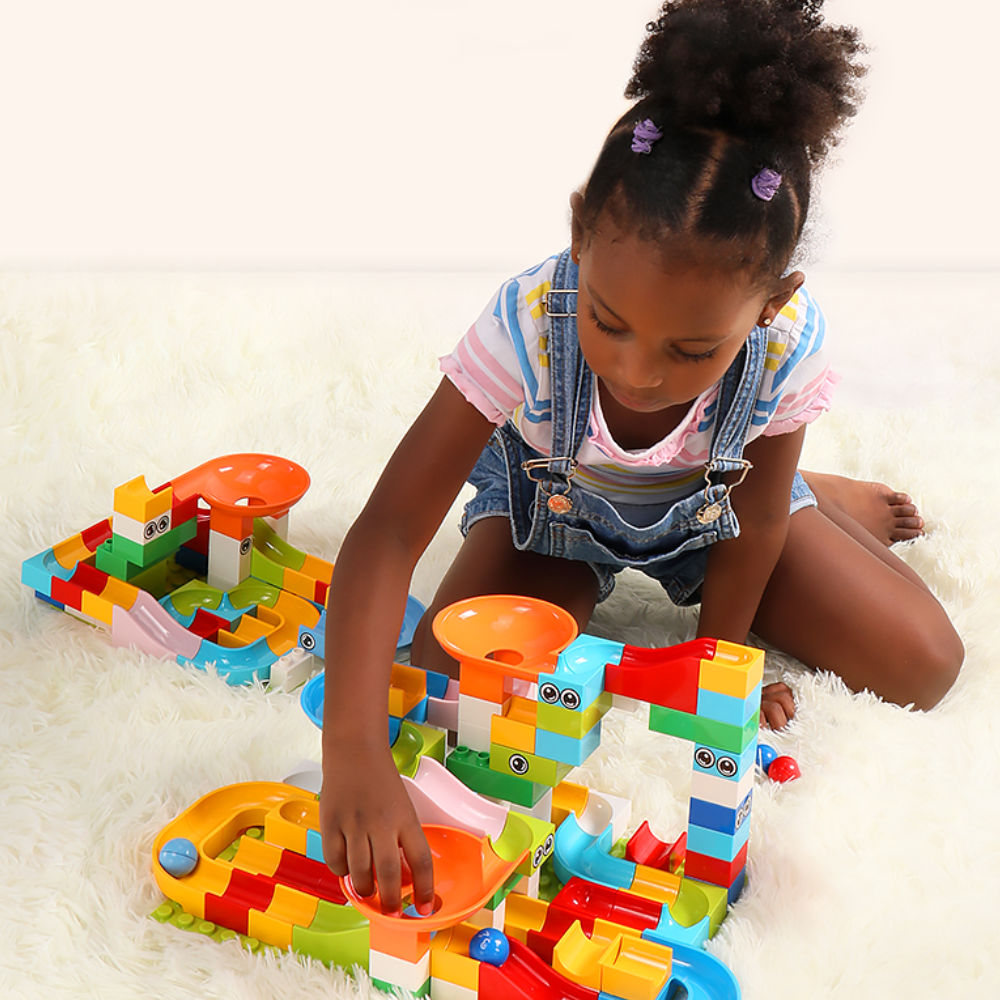 Child playing with a block marble run with orange funnels and colorful track pieces