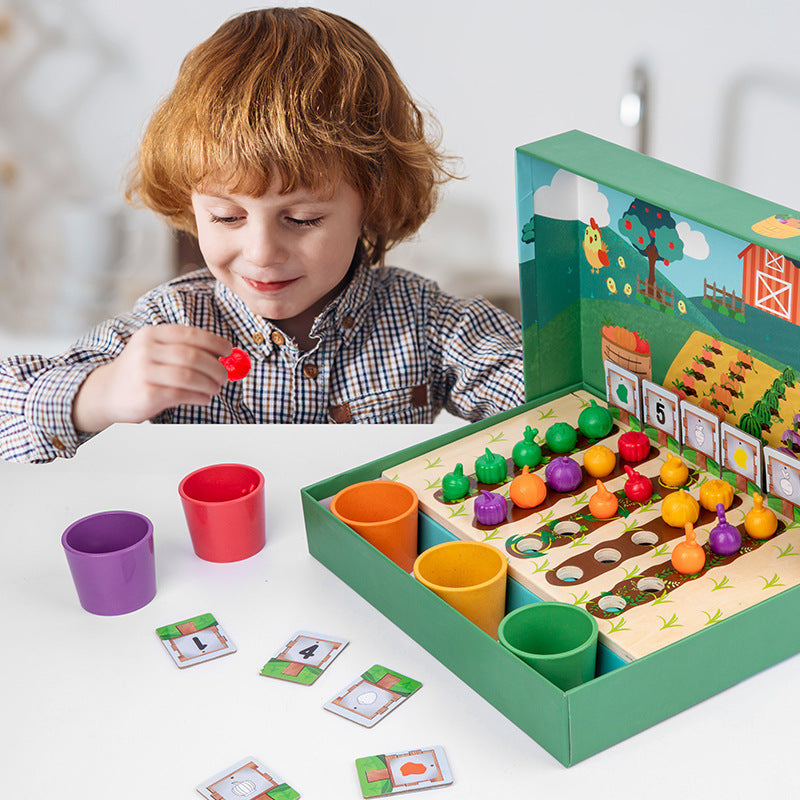 Child holding a red vegetable piece over the farm counting board with cups and number cards