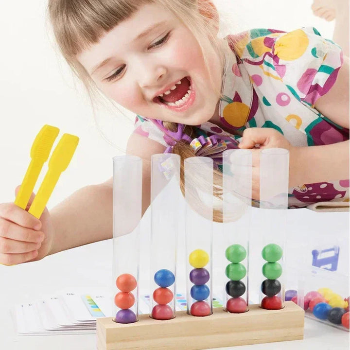 Child using a yellow clip beside clear tubes filled with colored wooden balls