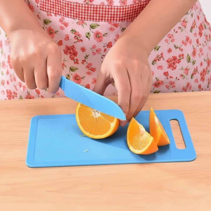 Child slicing an orange with a blue kitchen knife on a blue cutting board