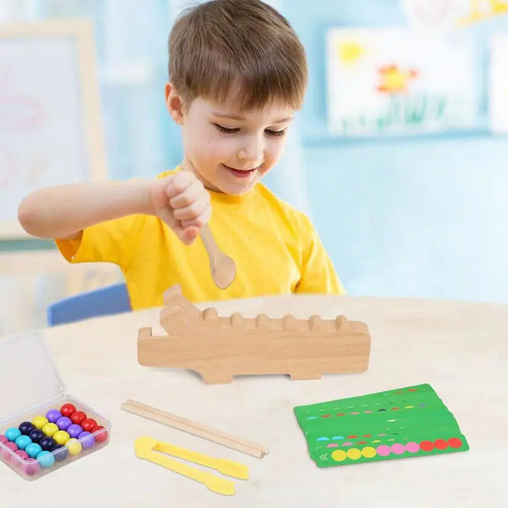 Child using a wooden spoon with the crocodile sorting board, beads, and pattern cards