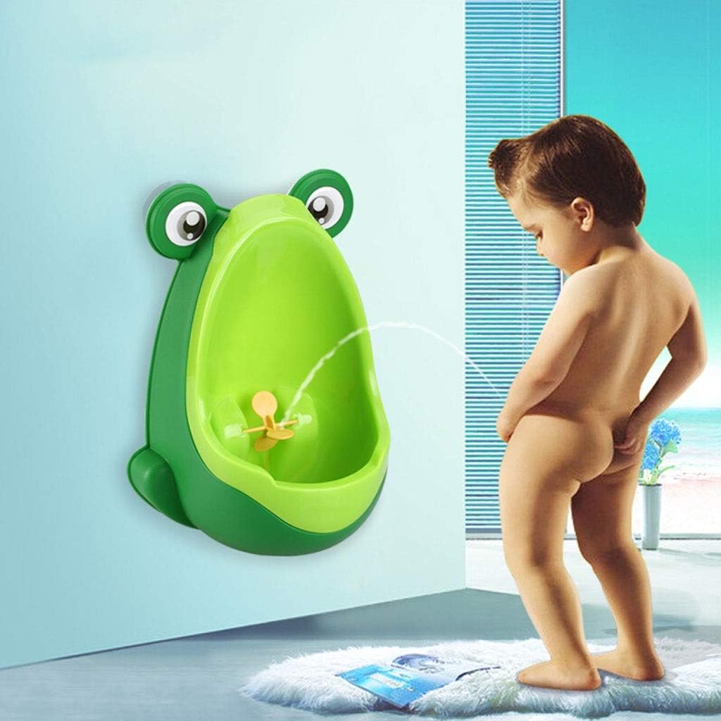 Child practicing standing potty training with a green frog urinal mounted on a bathroom wall