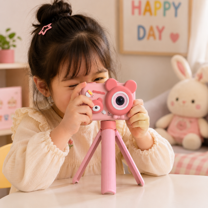 Child using a pink bear digital camera on its stand at a table