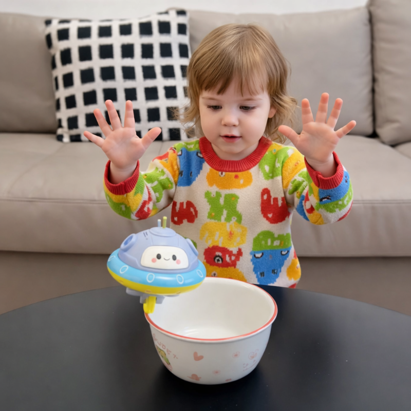Child watching a UFO balance toy on the rim of a bowl at a table.