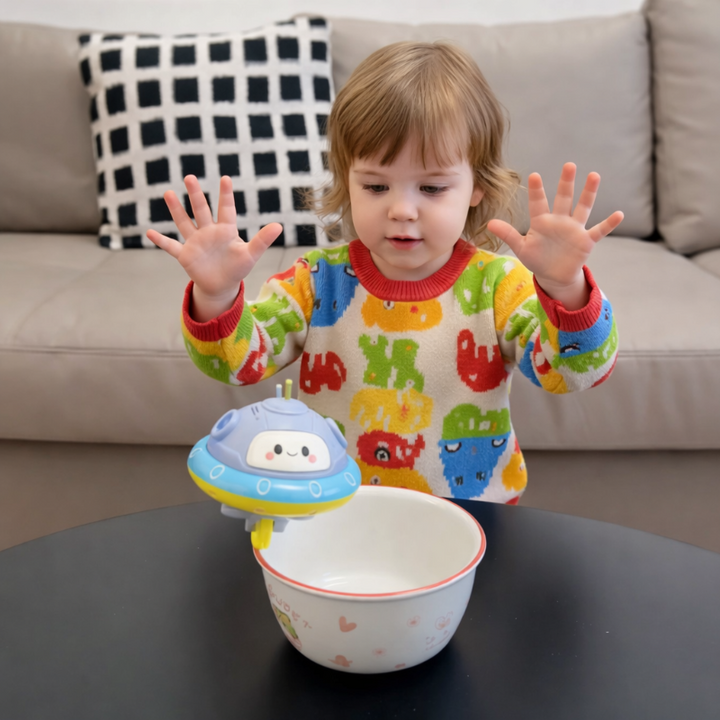 Child watching a UFO balance toy on the rim of a bowl at a table.