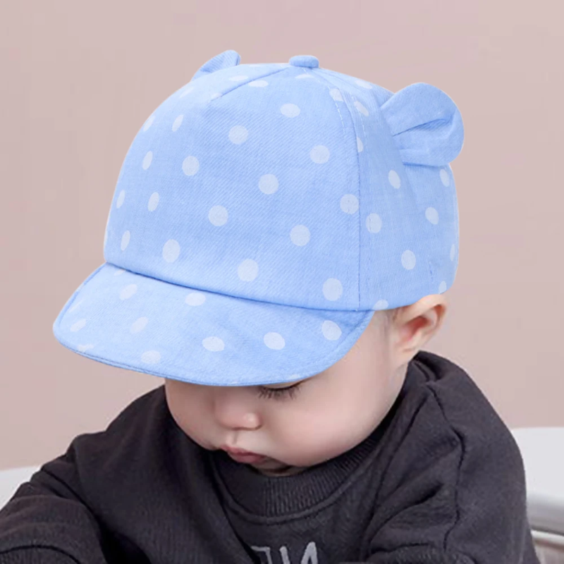 Child wearing a light blue polka dot cap with rounded fabric ears.