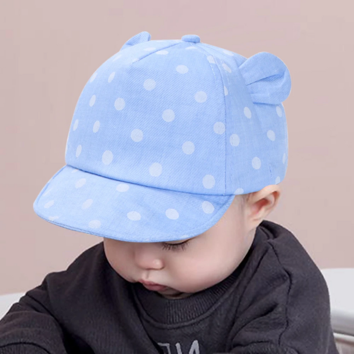 Child wearing a light blue polka dot cap with rounded fabric ears.