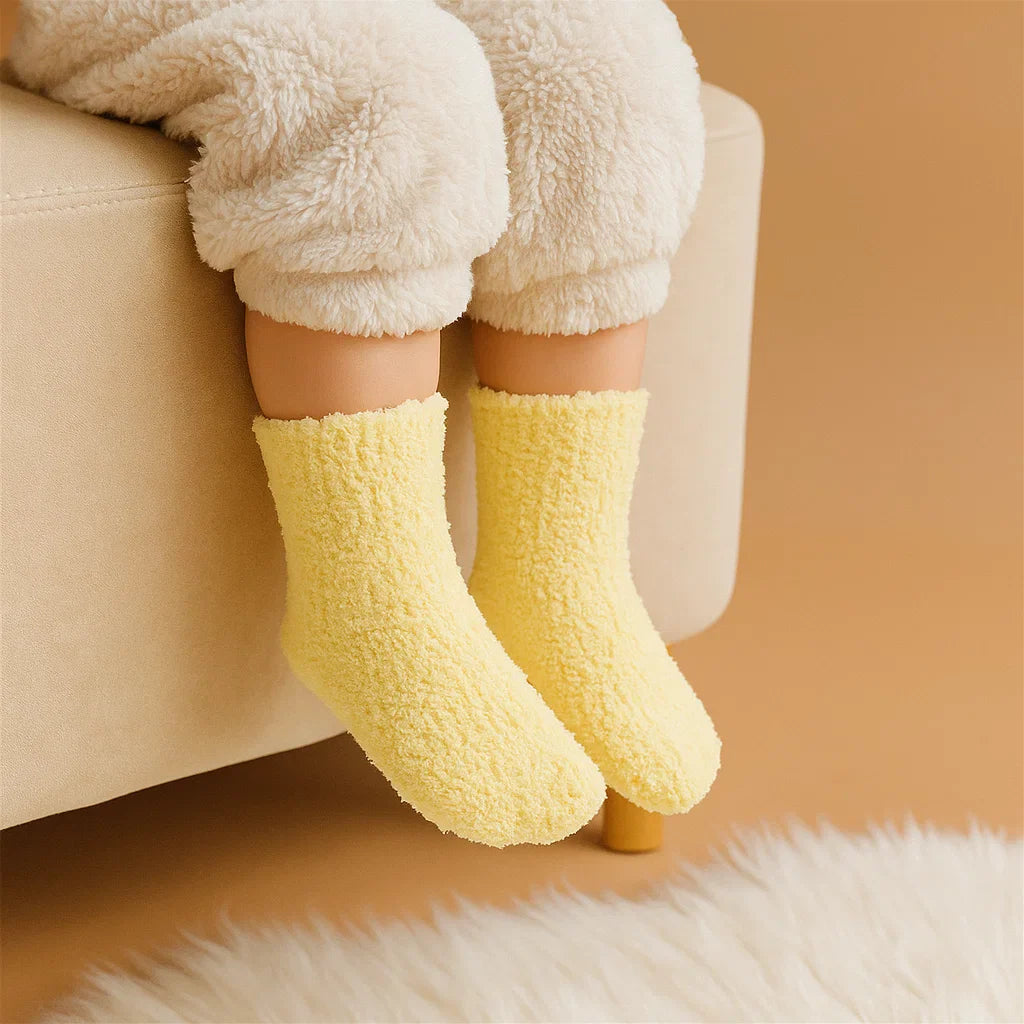 Child wearing yellow fleece socks while seated on a beige sofa.
