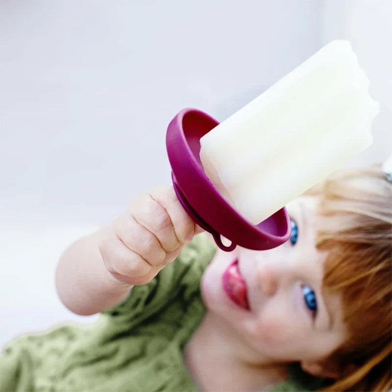 Child holding a white ice pop with a purple silicone drip catcher