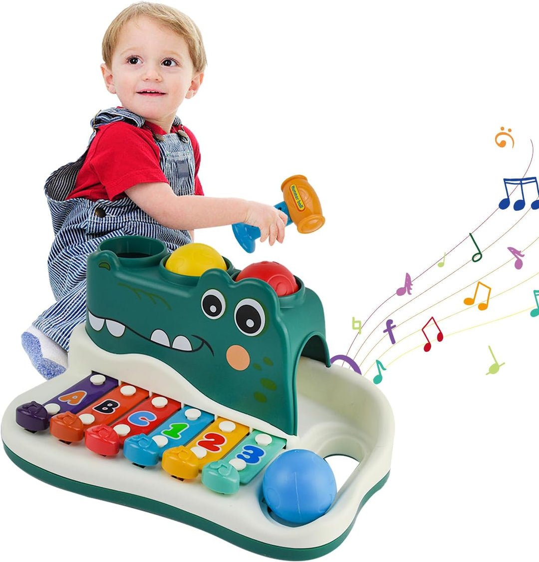 Child holding a hammer beside the alligator xylophone toy with a blue ball in its side tray