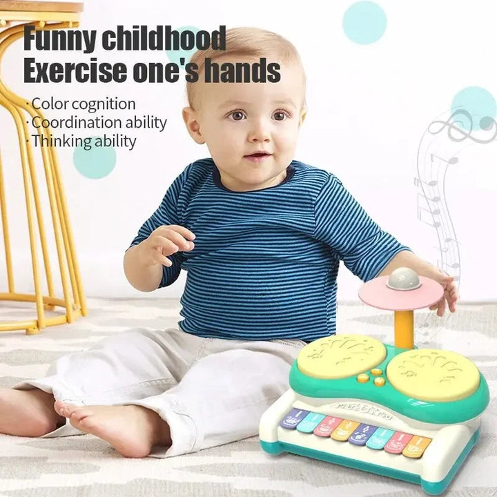 Child seated beside a green musical drum toy with yellow drum pads and colorful keys