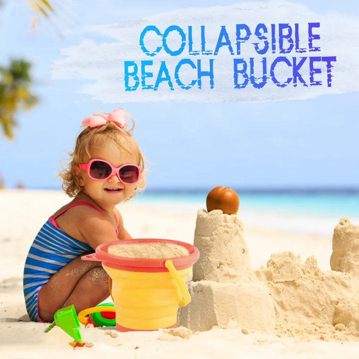 Child beside a sandcastle with a yellow beach bucket with a pink rim