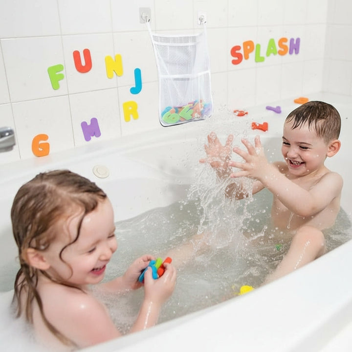 Two children playing in a bathtub with a white mesh toy organizer hanging on the tiled wall
