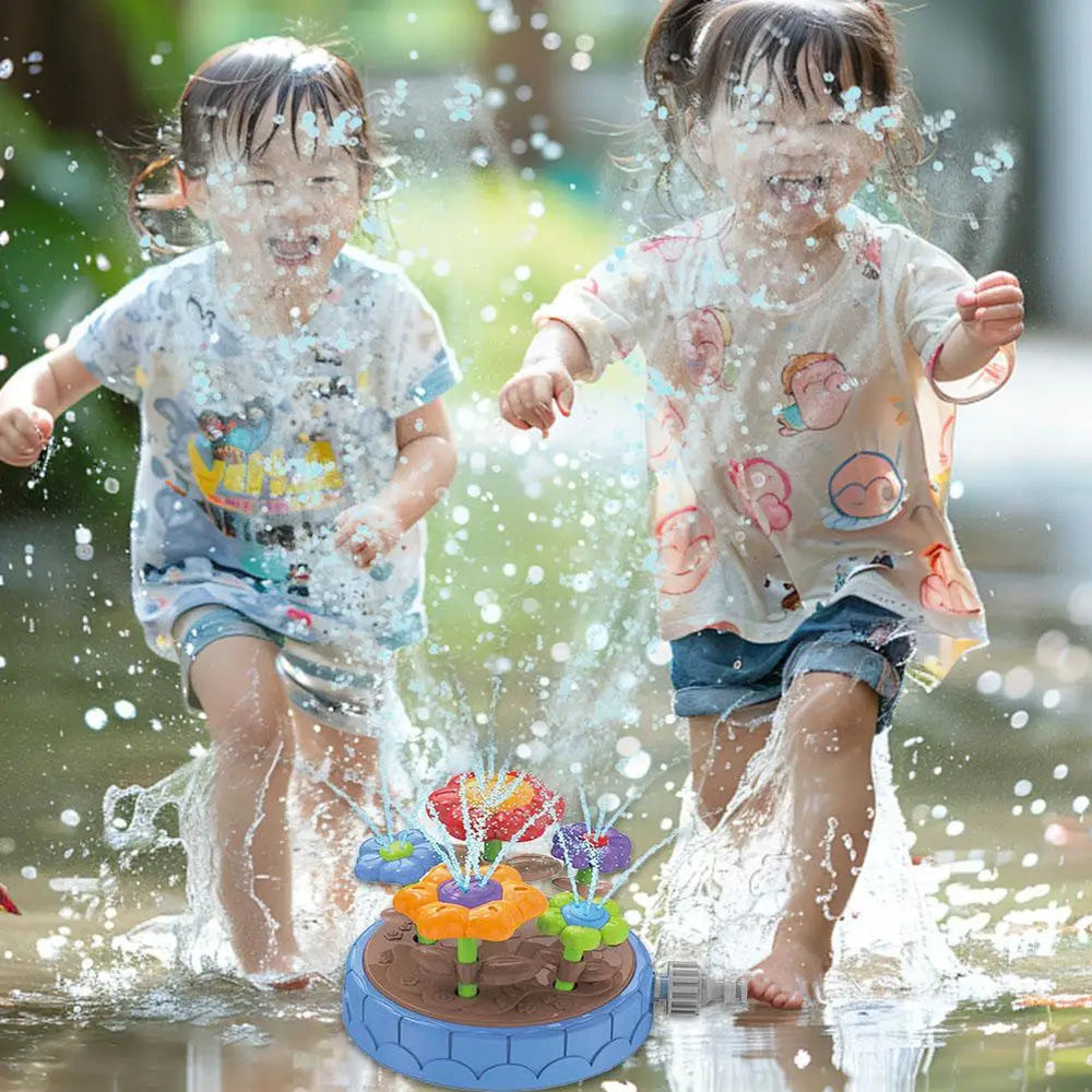 Two children splashing beside the blue flower sprinkler outdoors