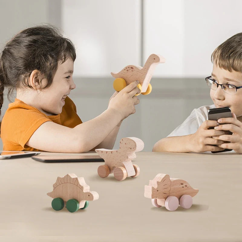 Two children playing with wooden dinosaur cars at a table