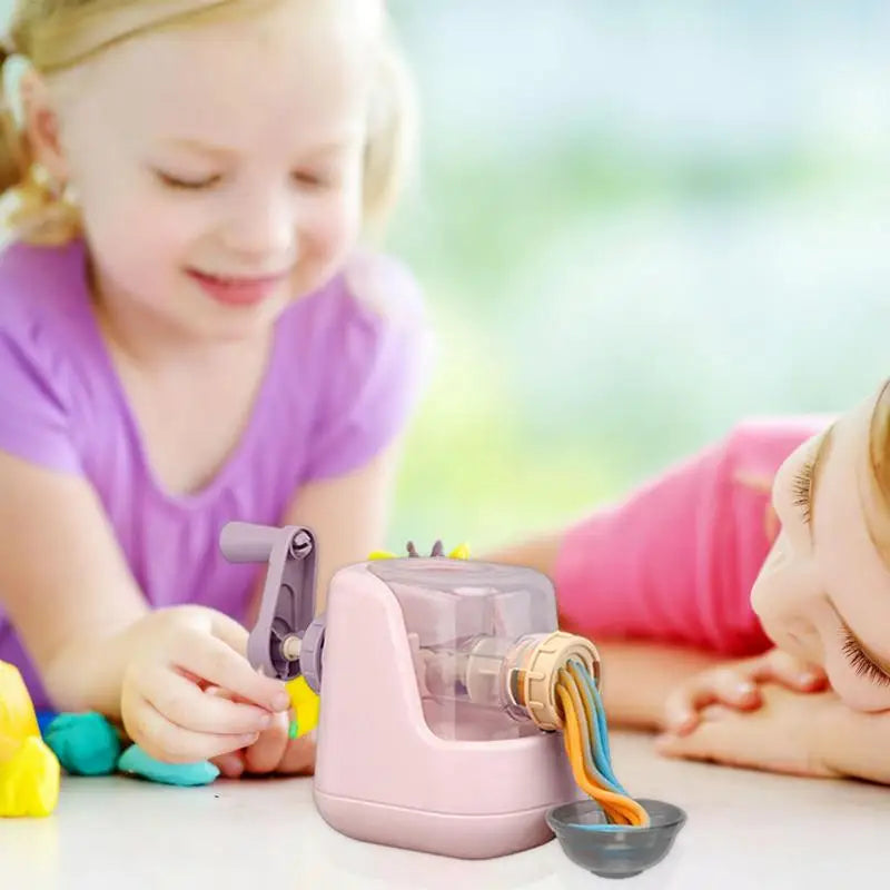 Children playing with a pink clay pasta maker as colorful noodles press into a bowl