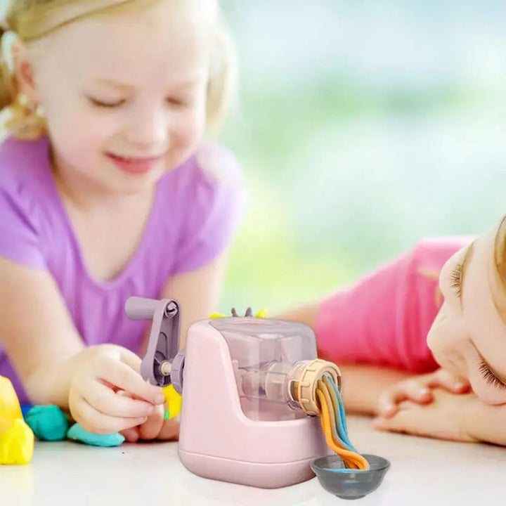 Children playing with a pink clay pasta maker as colorful noodles press into a bowl